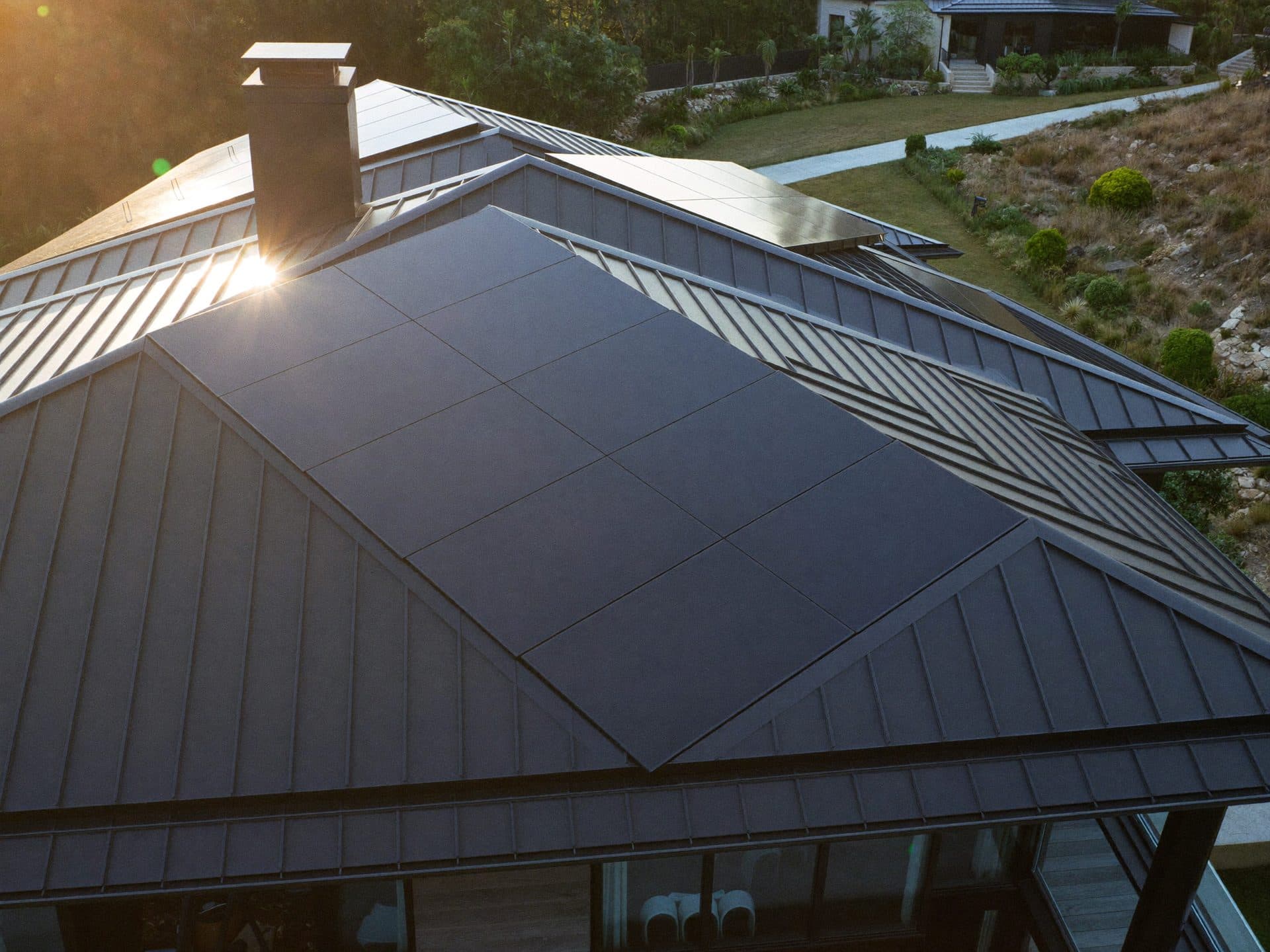 Black solar panels on a standing-seam roof catching golden-hour sun